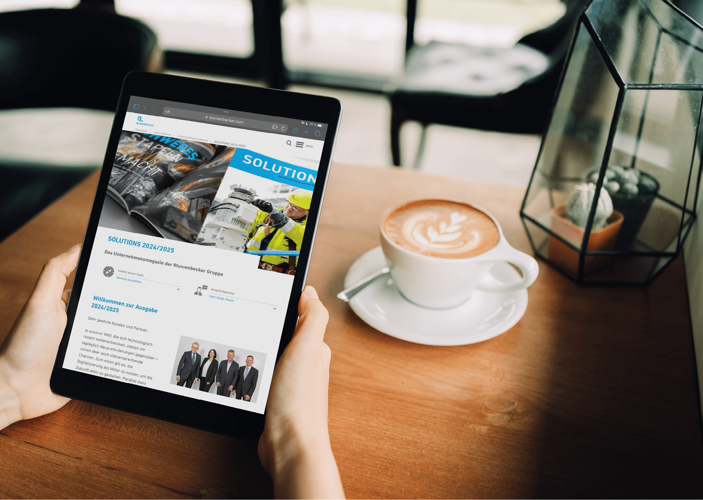 A woman hands are holding a mockup of black tablet with blank white screen  in the cafe with a white cup of latte coffee. sitting on the wood table, clipping path included